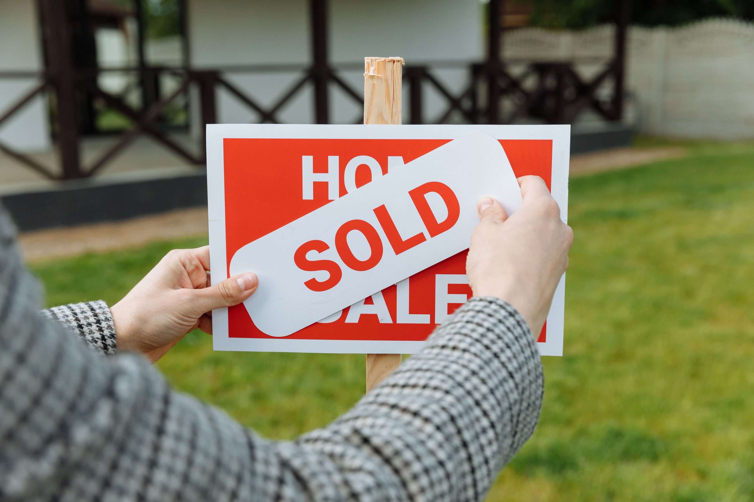 Mains apposant autocollant vendu panneau immobilier