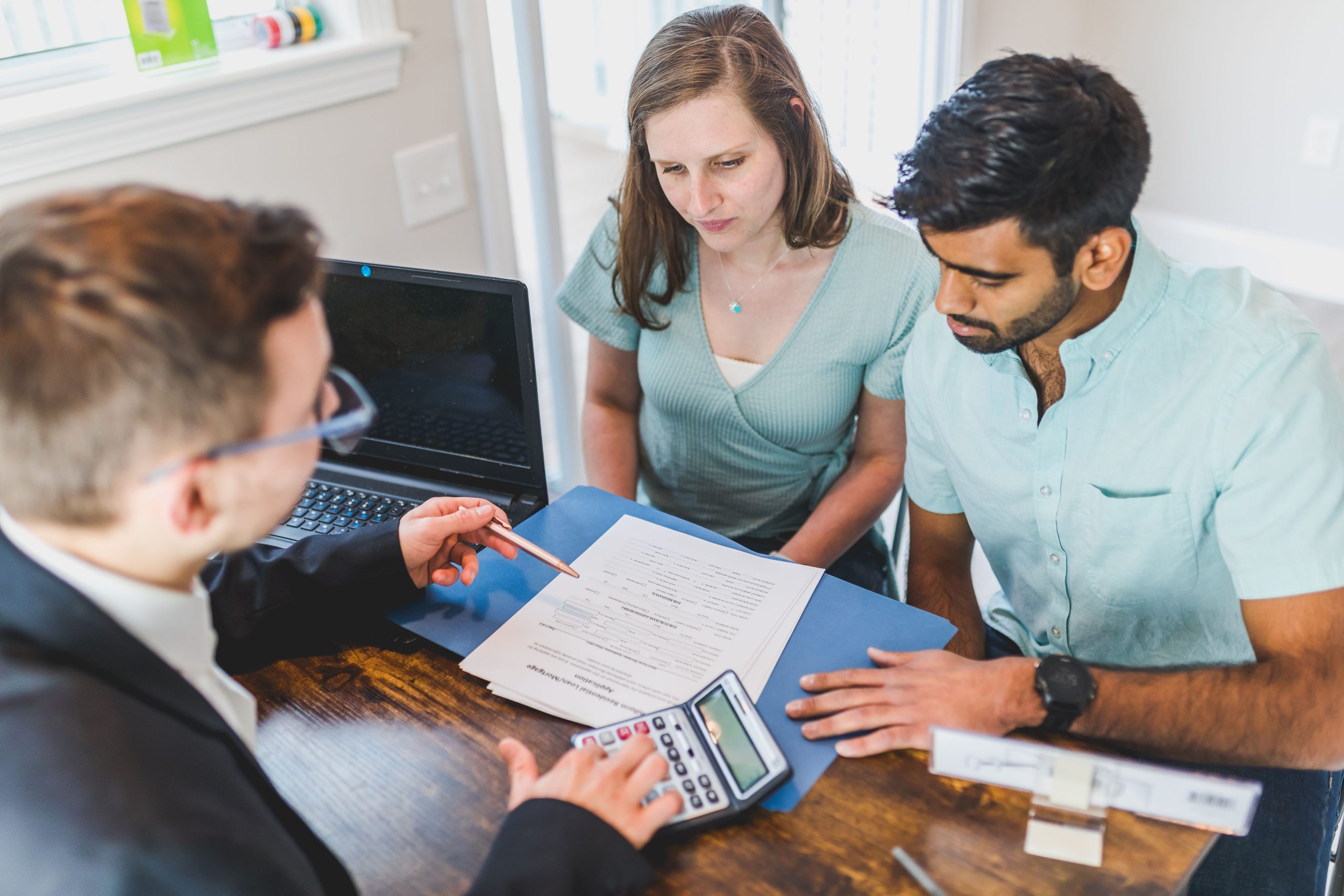 Couple primo-accédant discutant achat immobilier agent