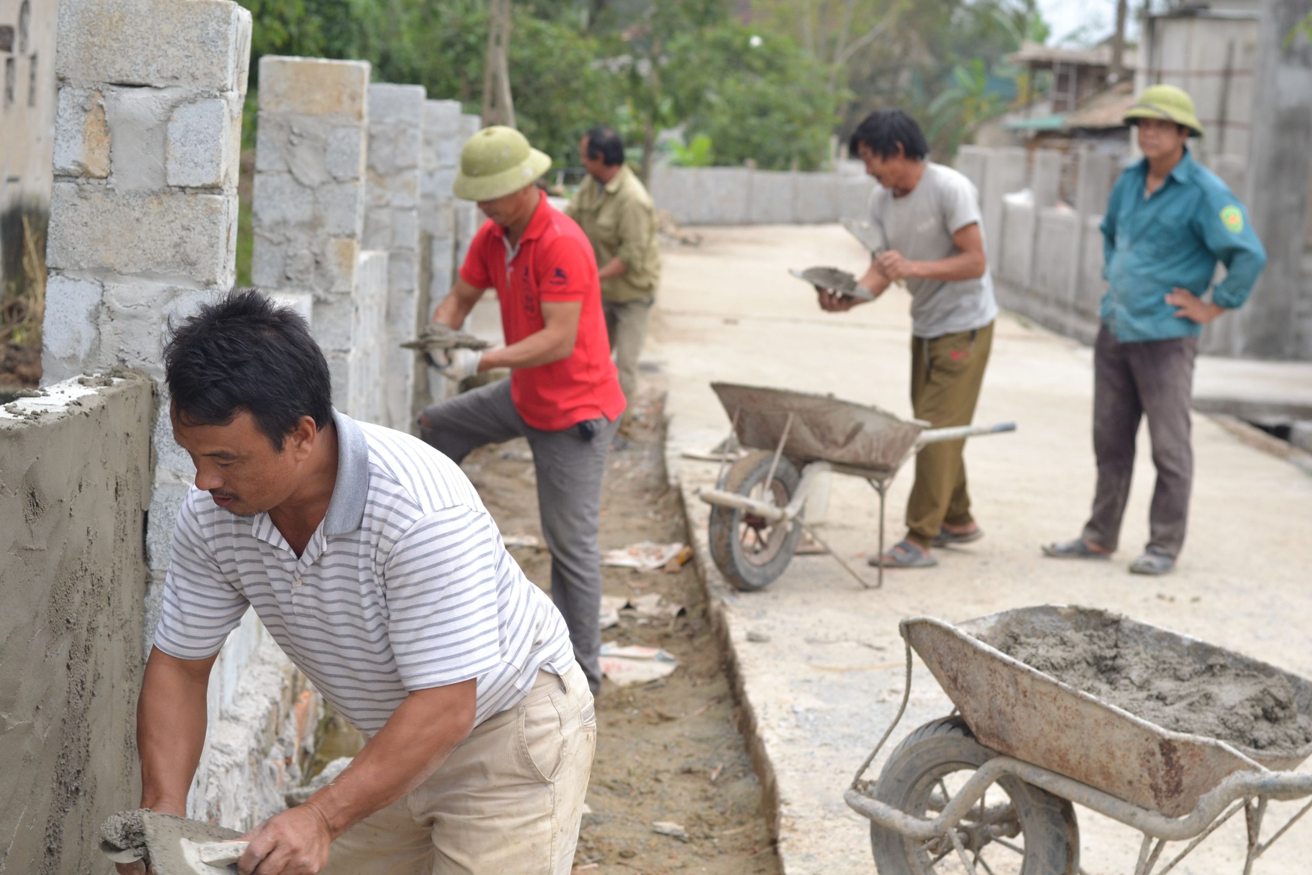 Ouvriers construisent mur pierre avec enduit