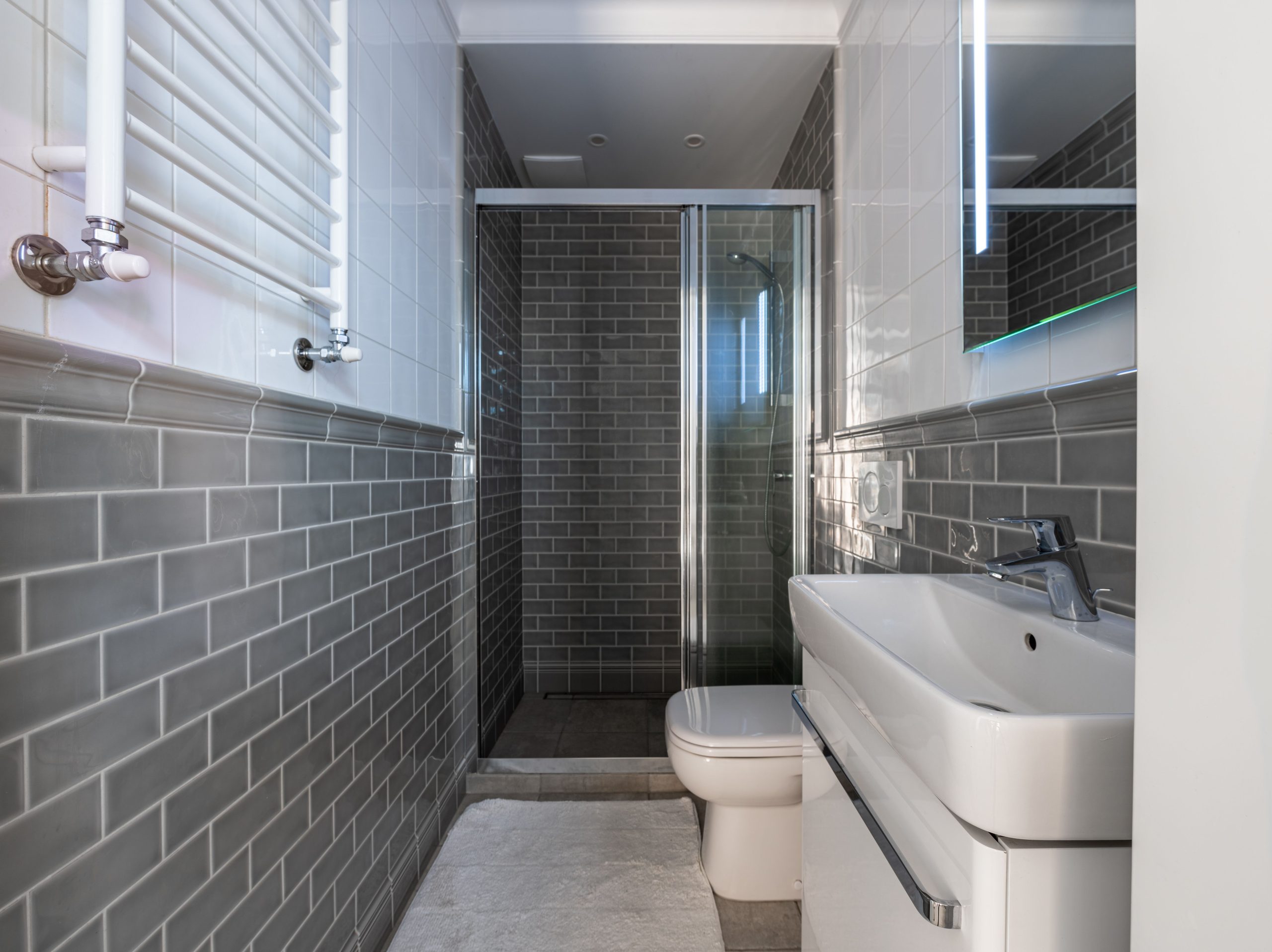 Salle de bain compacte avec carrelage gris et douche vitrée