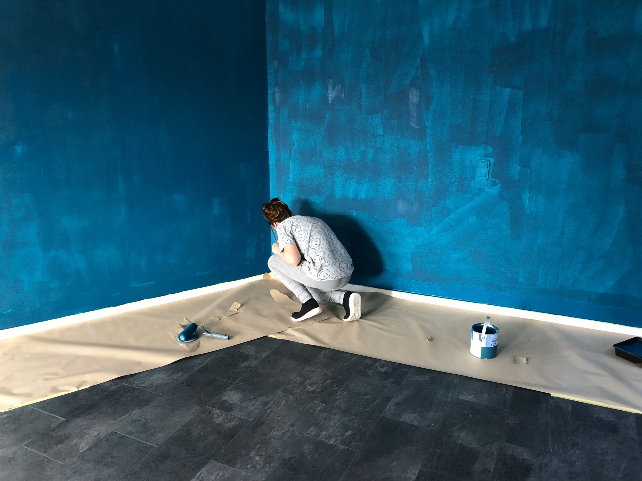 Femme peignant un mur bleu à l'intérieur