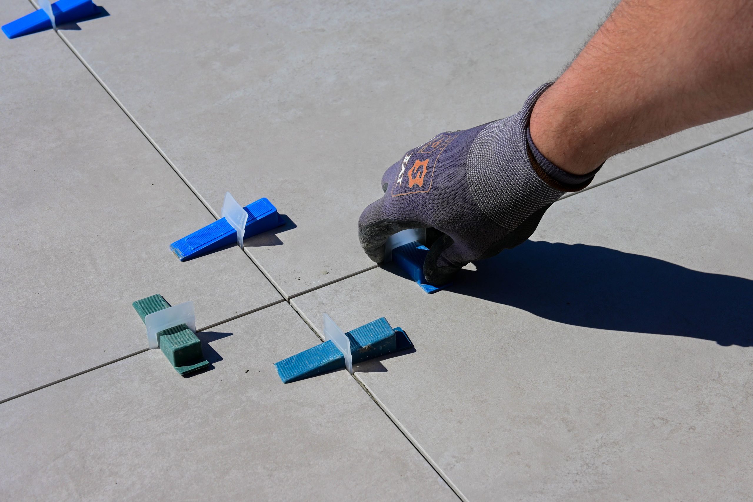 Main gantée posant des carreaux avec cales d'espacement